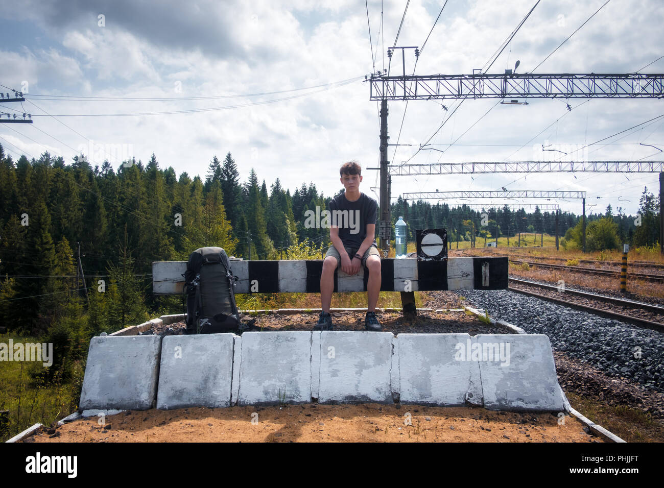 Teenager on railway station sitting with baclpack Stock Photo