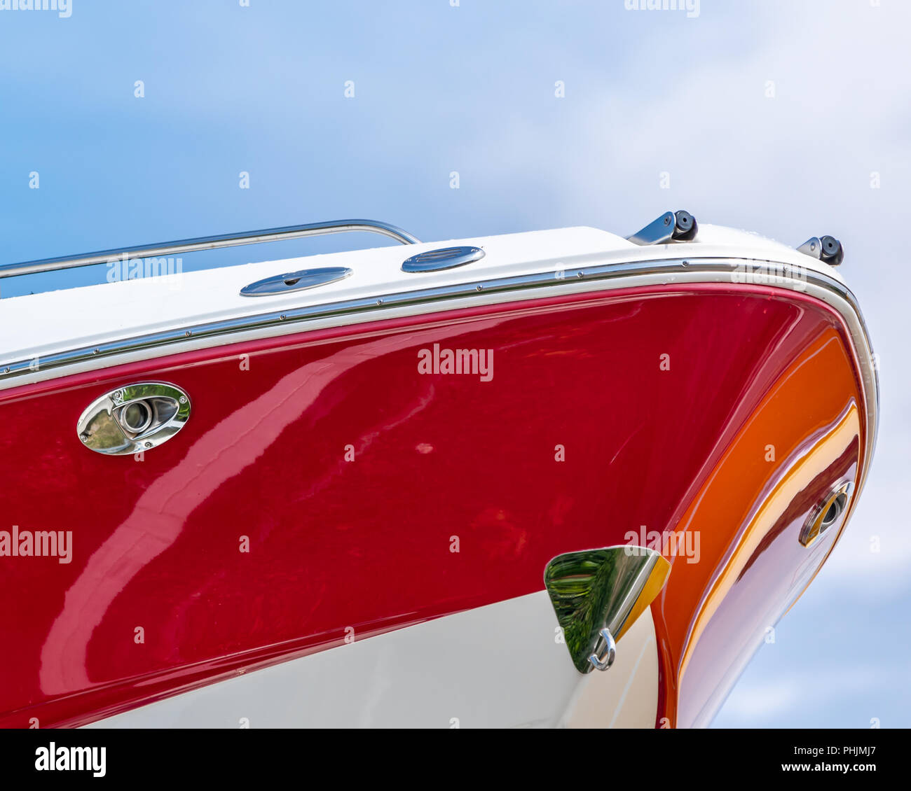 detail image of a the bow of a red and white fiberglass boat against a blue sky Stock Photo