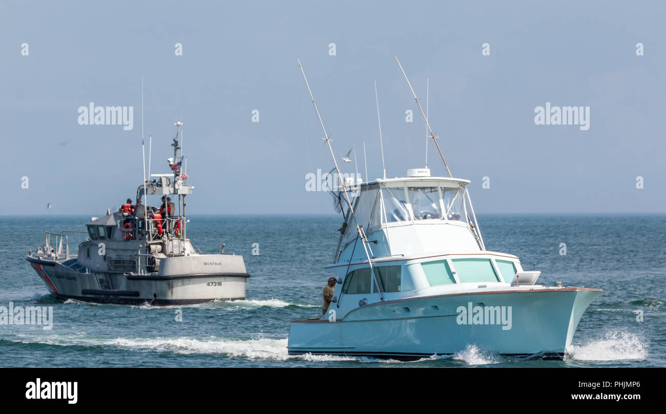 US Coast Guard boat passing a private fishing boat, Montauk, NY Stock Photo