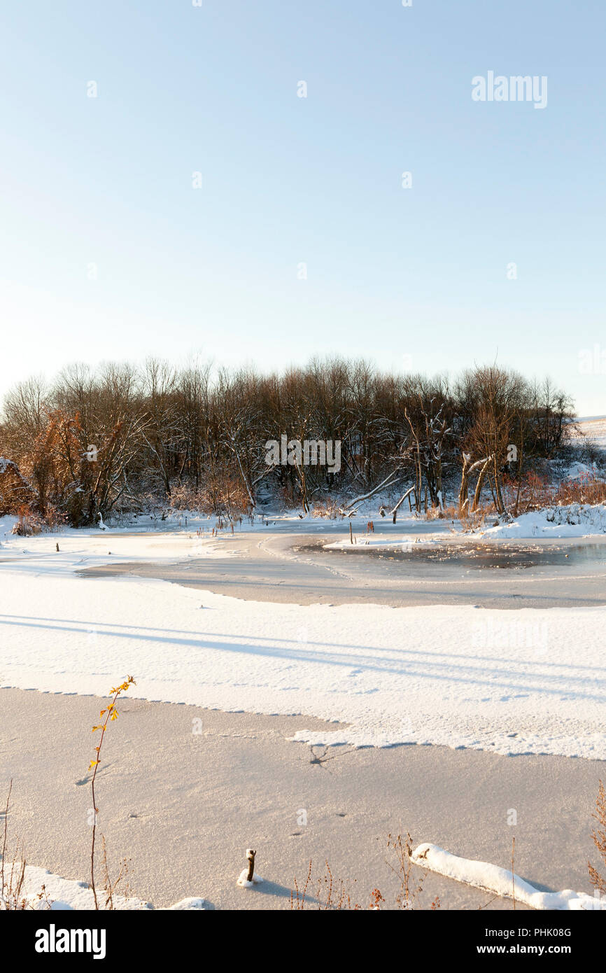 frozen lake and forest in the winter season, snow lies after a snowfall Stock Photo