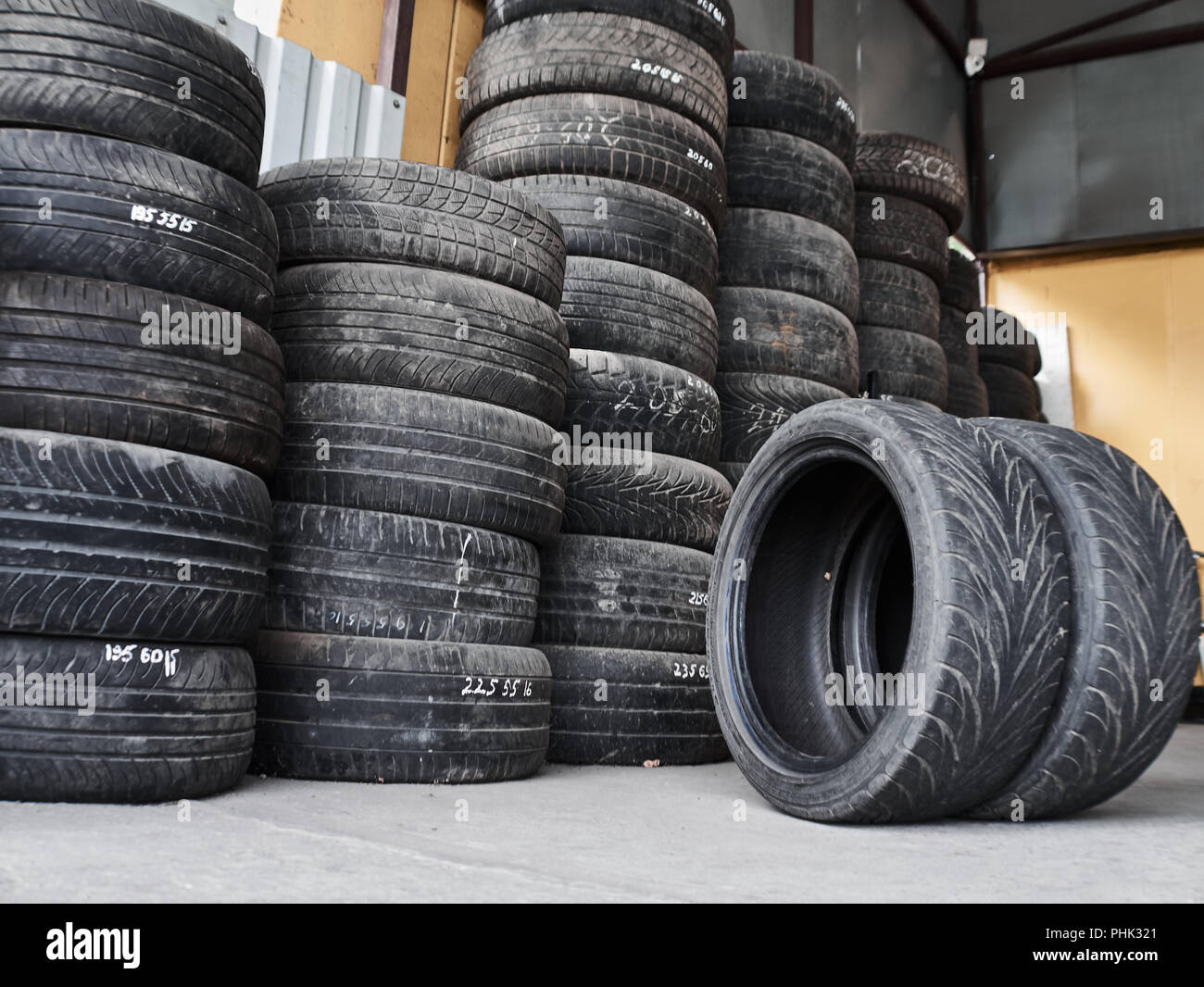 Used car tires stacked in piles at tire fitting service. Wheels for
