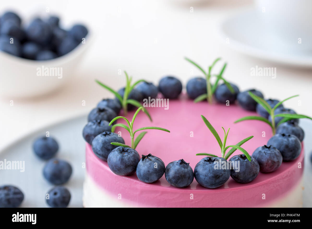 The two-color blueberry mini cheese cake. Round no bake cheesecake, bowl with blueberries, cup of coffee and bowl with sugar. Top of cake decorated by Stock Photo