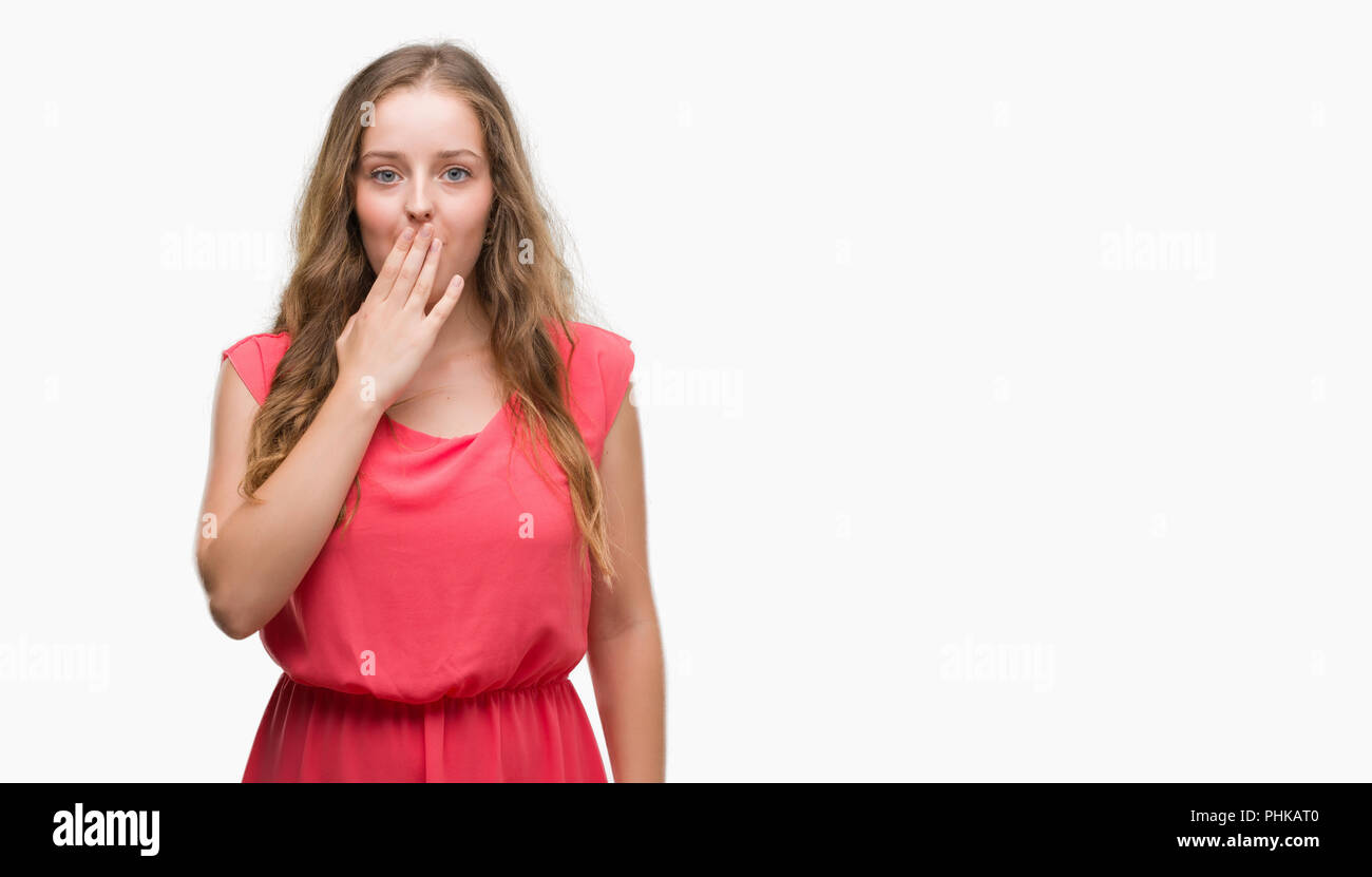 Young blonde woman wearing pink dress cover mouth with hand shocked with shame for mistake, expression of fear, scared in silence, secret concept Stock Photo