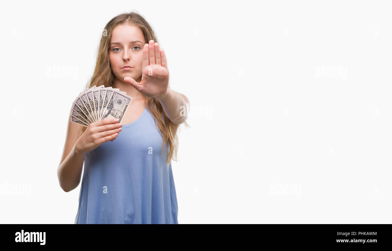 Young blonde woman holding dollars with open hand doing stop sign with serious and confident expression, defense gesture Stock Photo