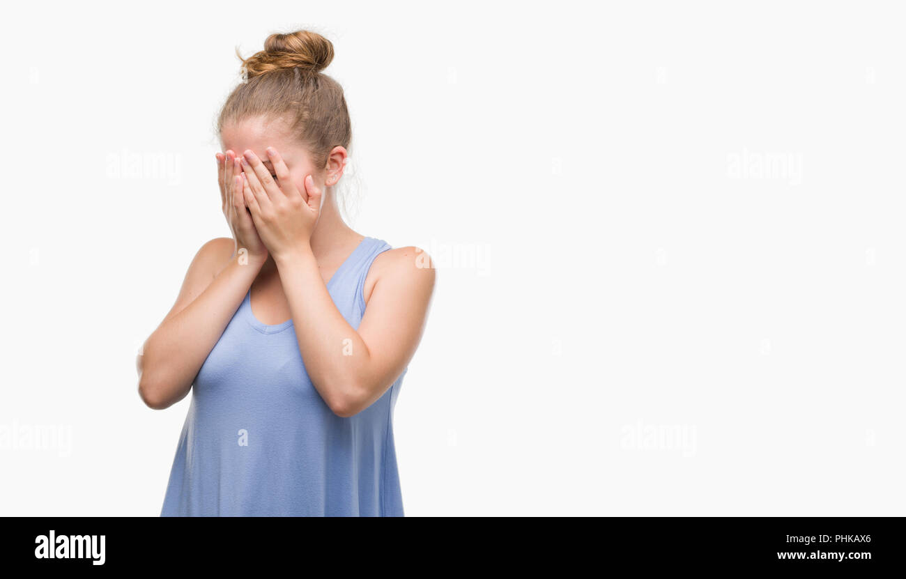 Young blonde woman with sad expression covering face with hands while crying. Depression concept. Stock Photo