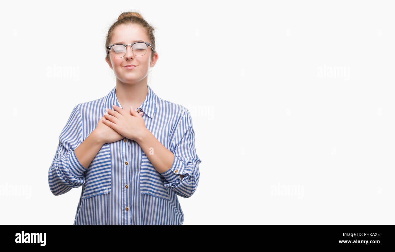 Young blonde business woman smiling with hands on chest with closed eyes and grateful gesture on face. Health concept. Stock Photo