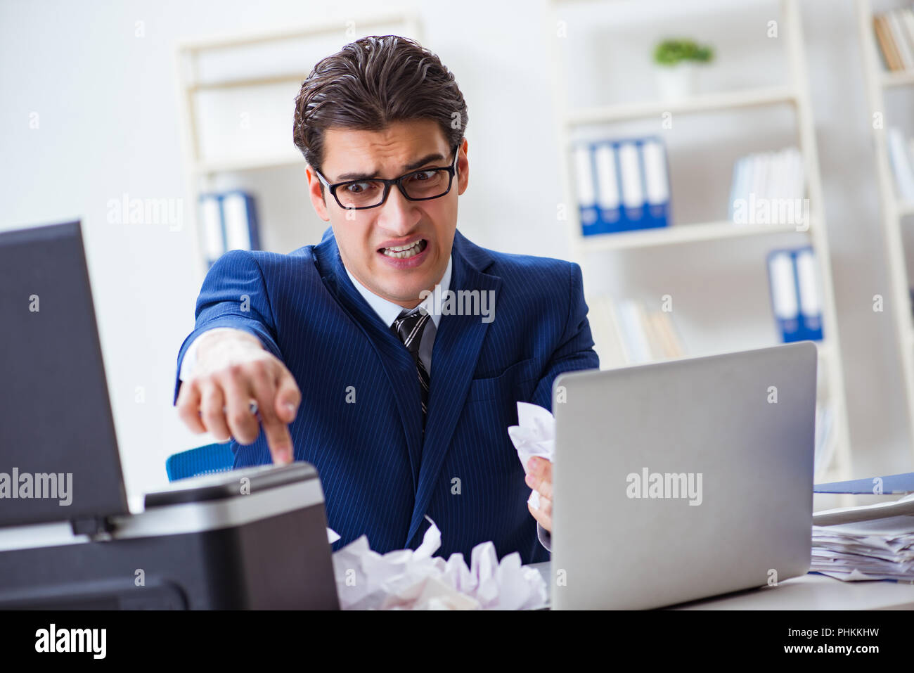 Businessman angry at copying machine jamming papers Stock Photo - Alamy