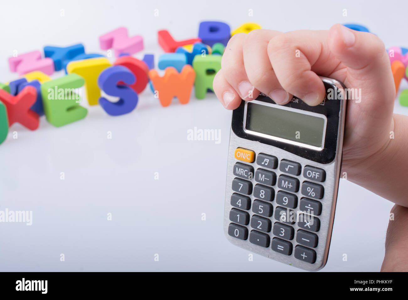 Little calculator in hand with colorful letters behind on white Stock