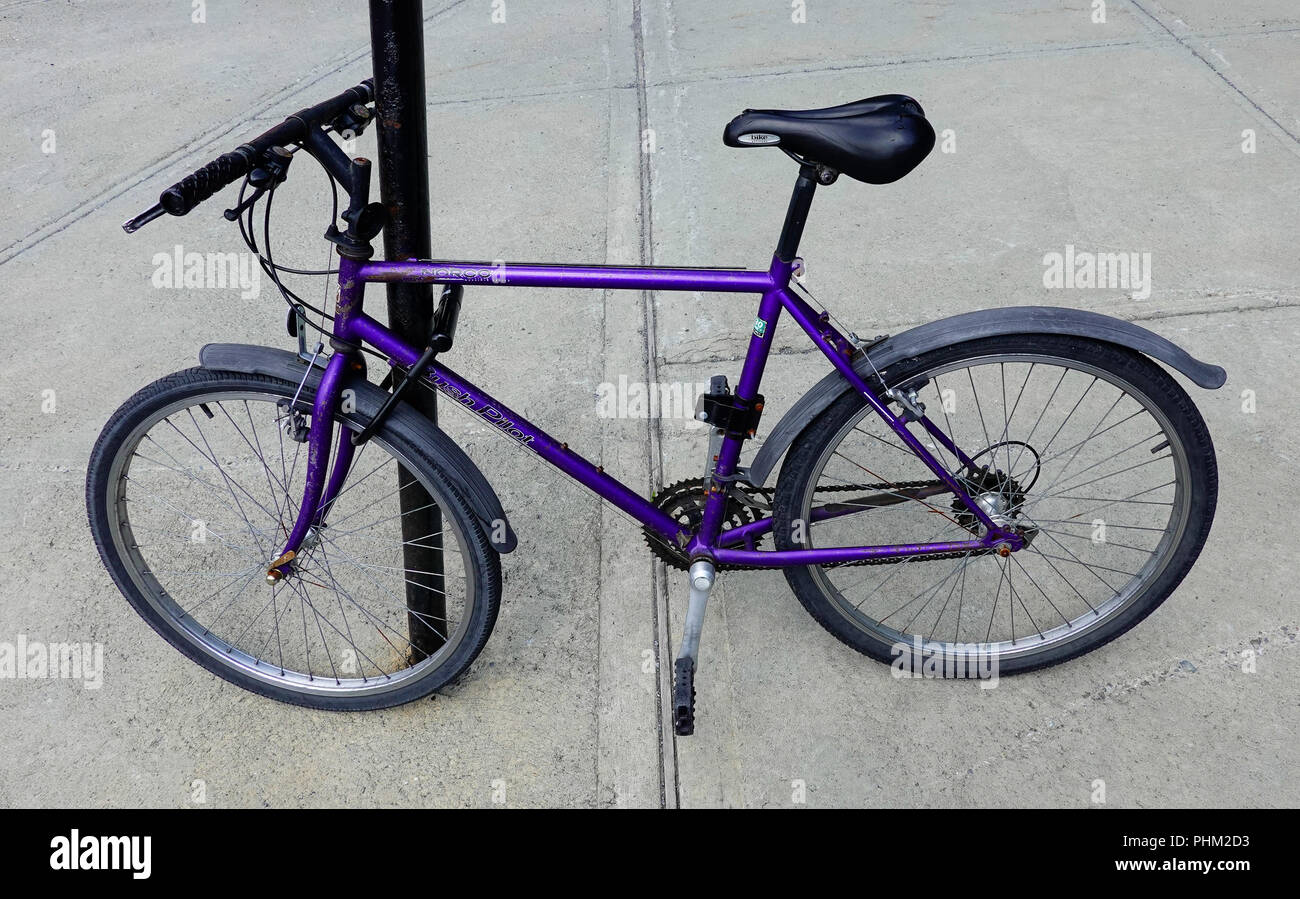 Purple bicycle chained to post in Montreal, QC, Canada Stock Photo