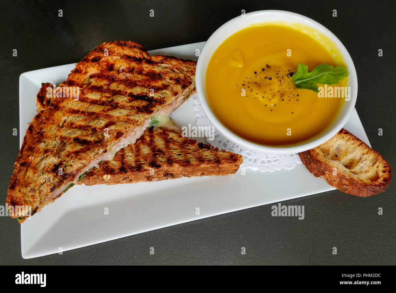 Creamy pumpkin soup and a grilled ham and cheese sandwich Stock Photo
