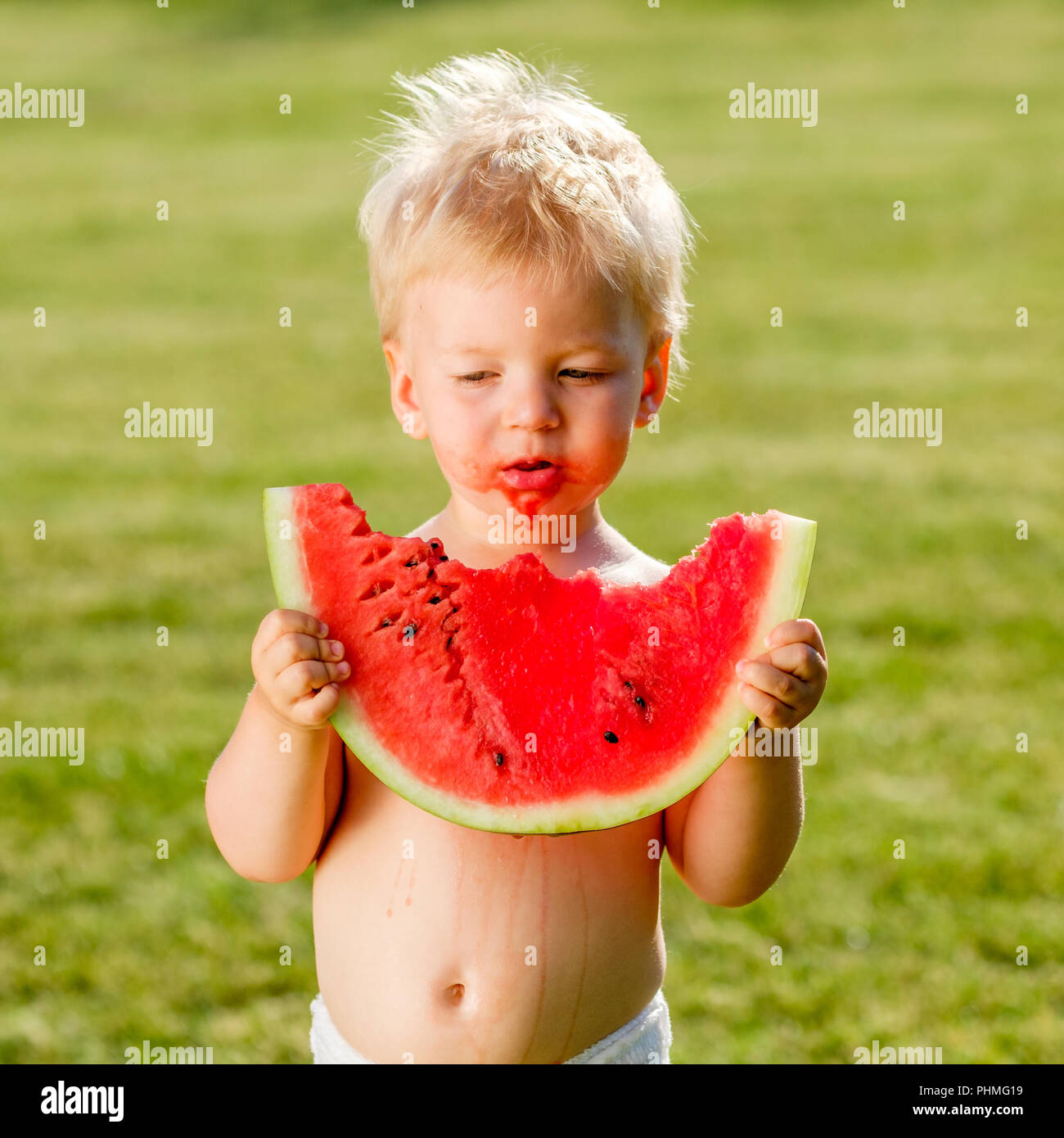 One year old baby boy eating watermelon in the garden Stock Photo