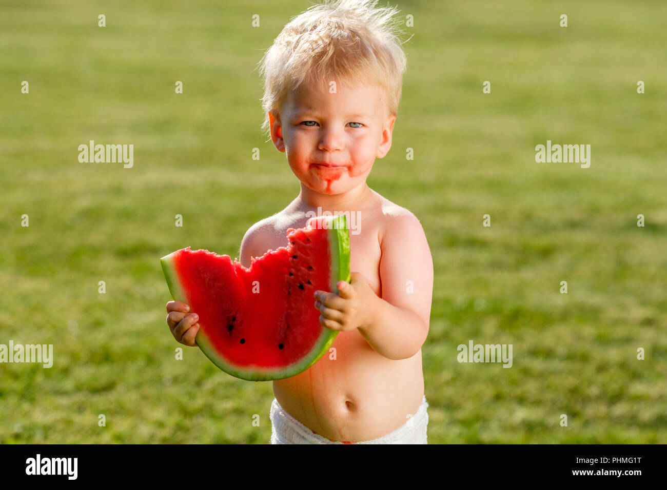 One year old baby boy eating watermelon in the garden Stock Photo