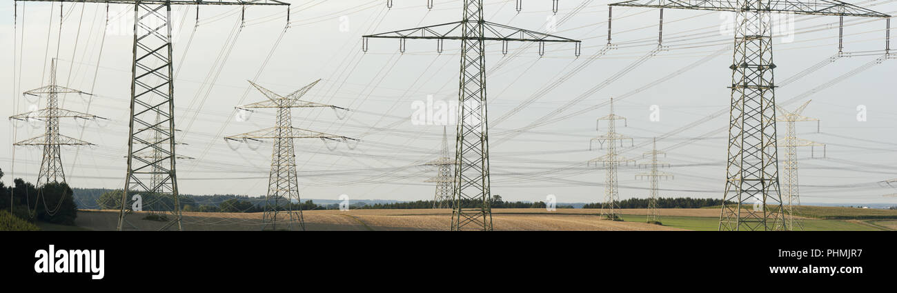 Many high-voltage pylons for transporting electricity from a power plant Stock Photo