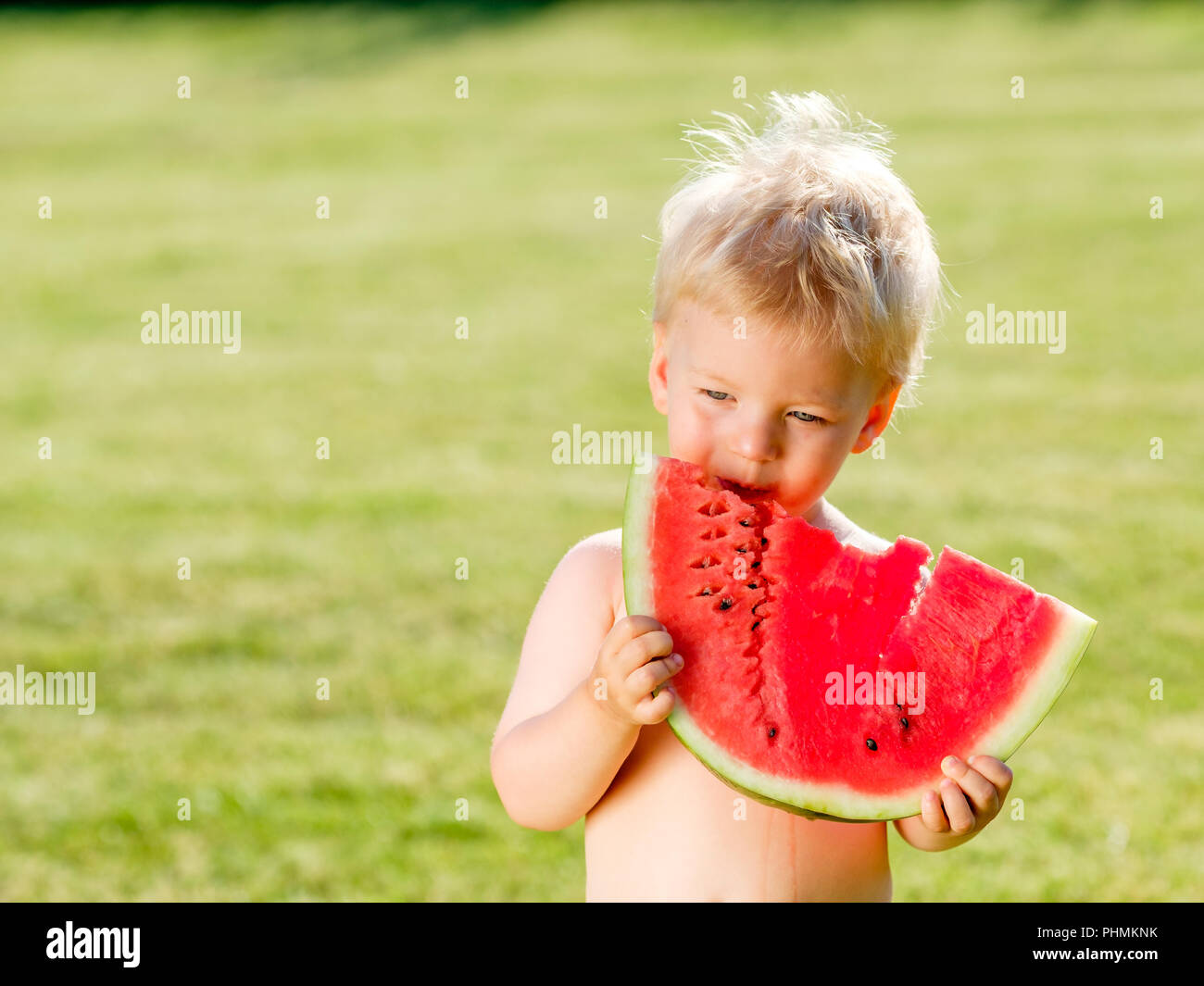 One year old baby boy eating watermelon in the garden Stock Photo