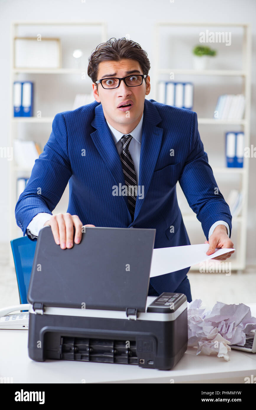 Businessman angry at copying machine jamming papers Stock Photo Alamy