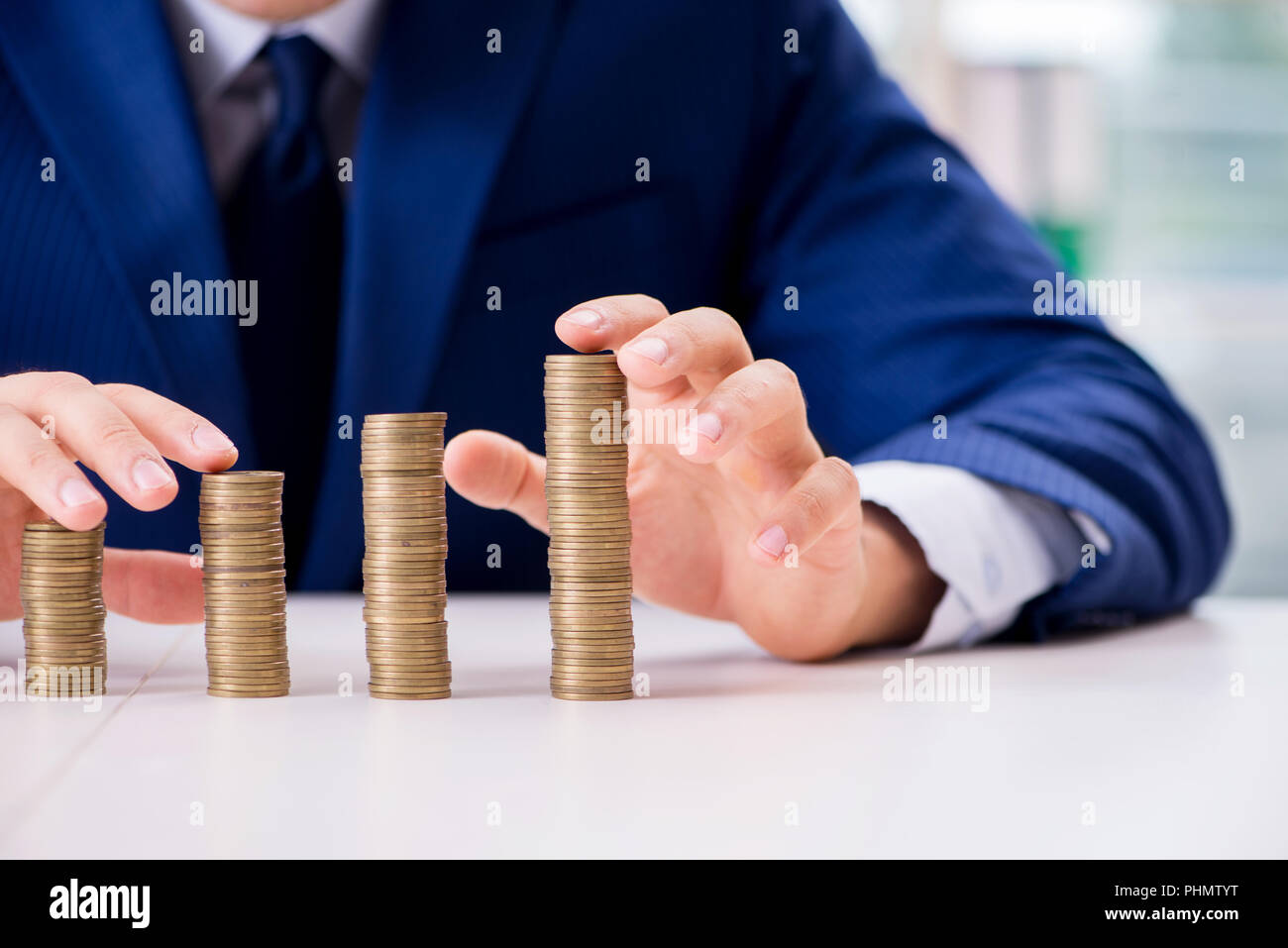 Businessman with stacks of coins in the office Stock Photo - Alamy