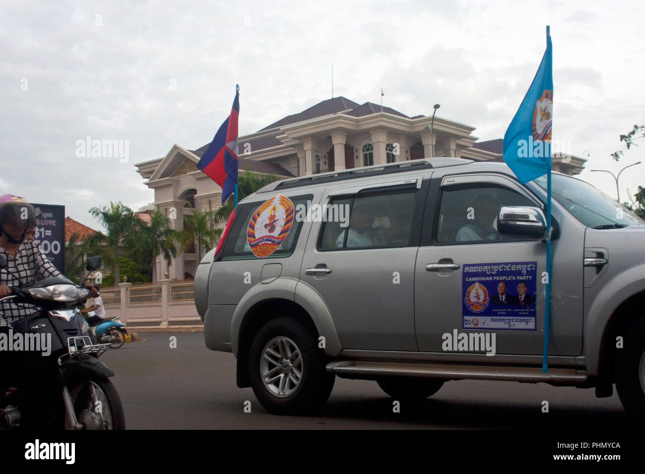 CPP supporters pass PM Hun Sen's brother's (Hun Neang) mansion on a city street during a campaign rally in Kampong Cham, Cambodia. Stock Photo