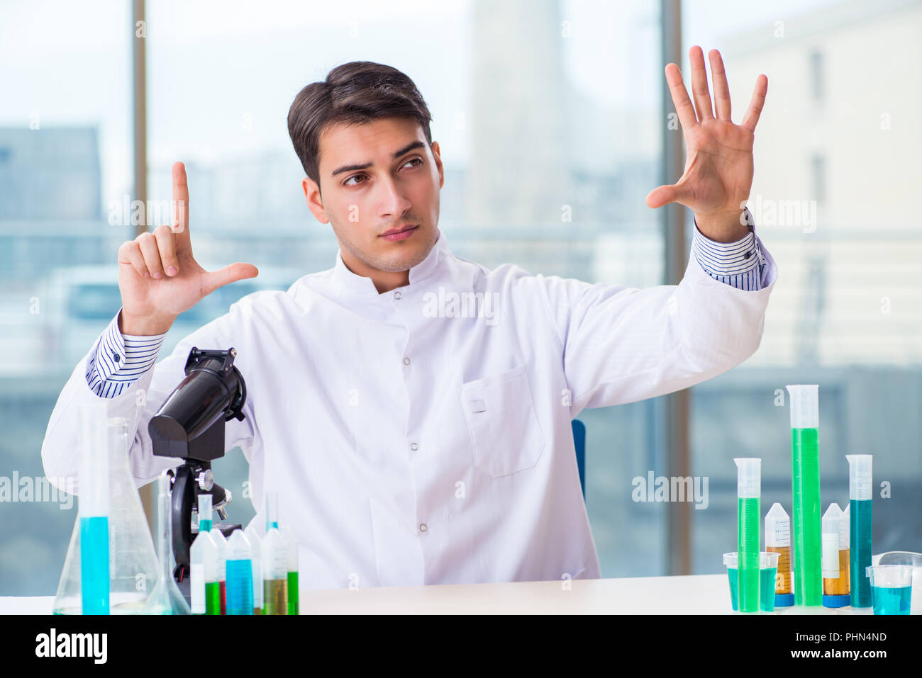 Young chemist pressing virtual buttons in lab Stock Photo