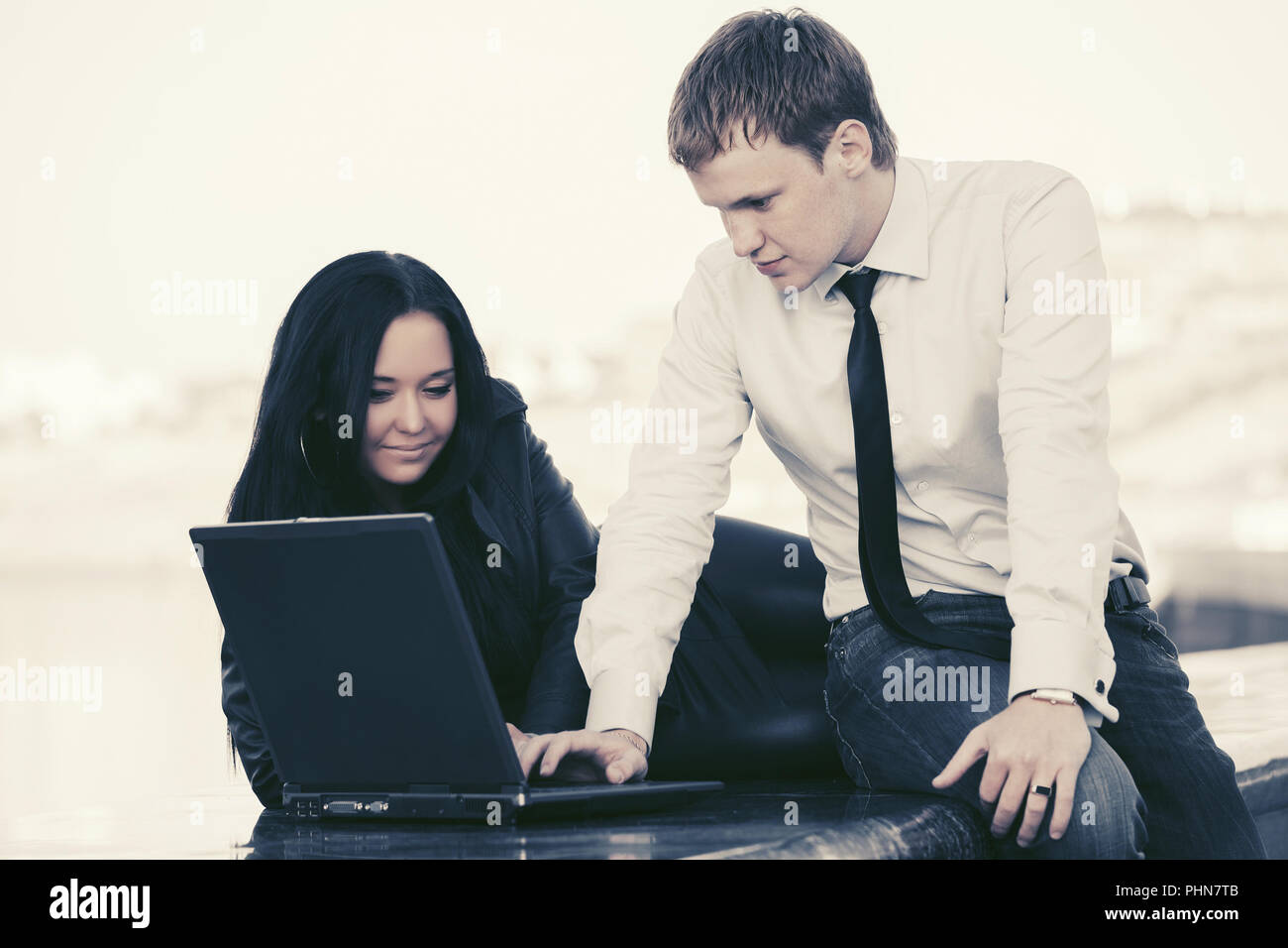 Young business couple using laptop outdoor Stock Photo - Alamy