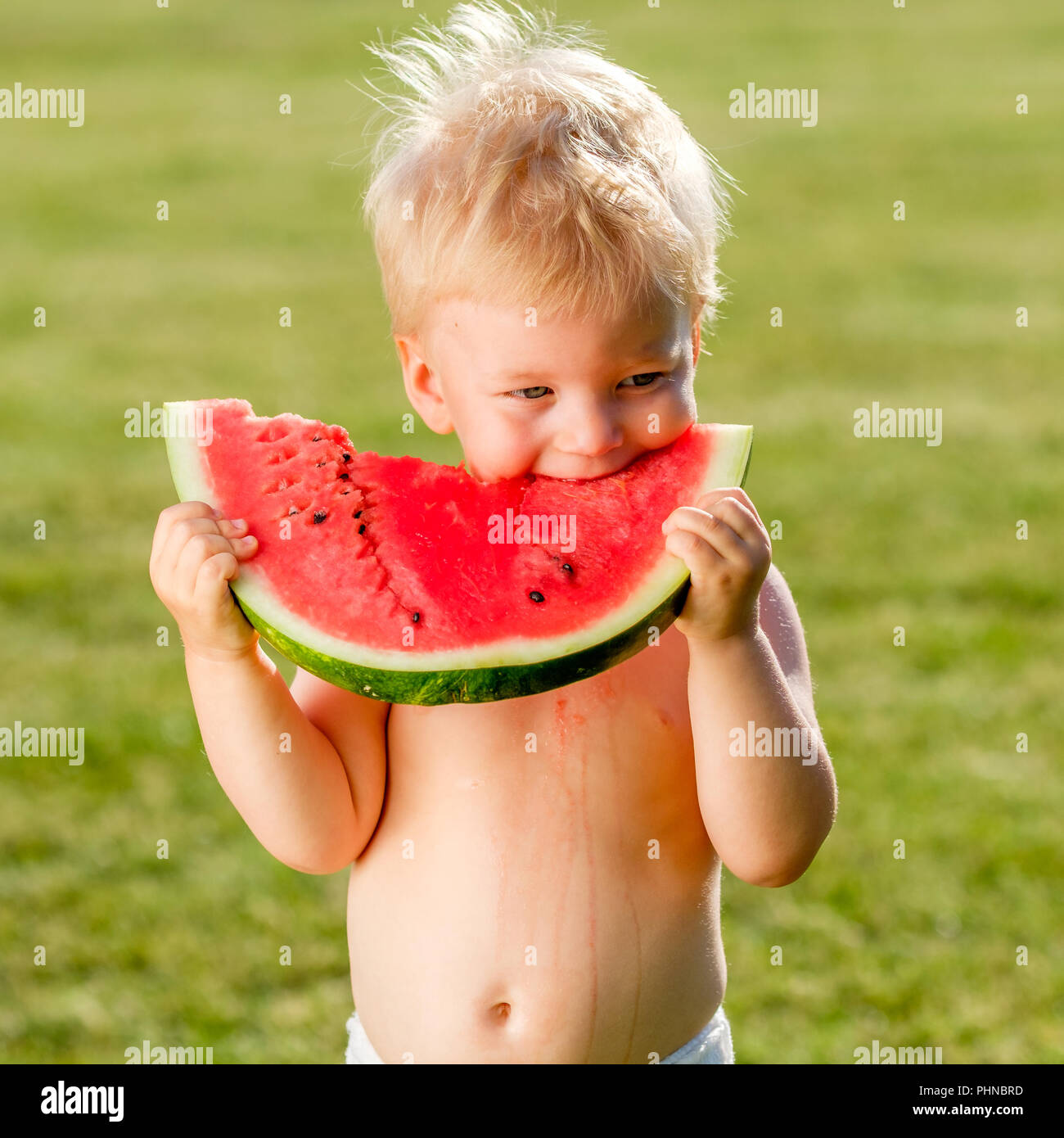 One year old baby boy eating watermelon in the garden Stock Photo