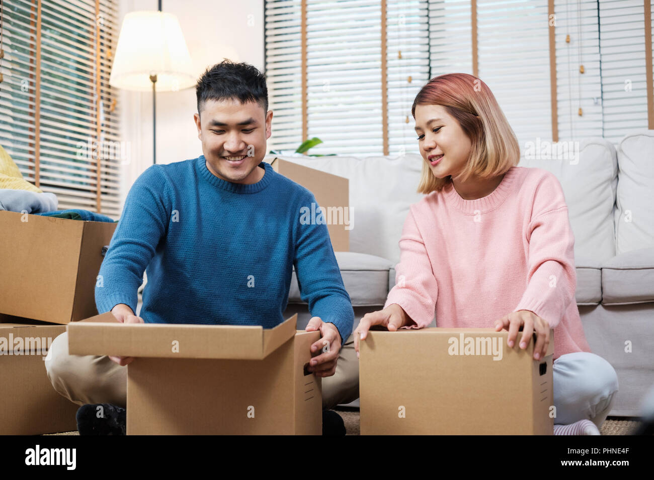 Happy asian couple open cardboard boxes while moving to new home at ...