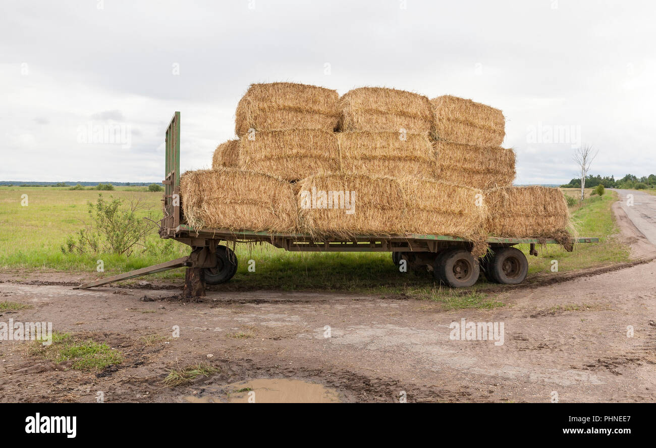 folded on a broken trailer, the wheel fell off, stacks of yellow straw