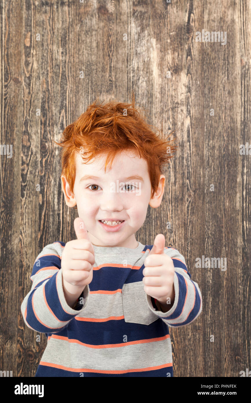 red-haired tousled boy holding thumbs up, close-up Stock Photo