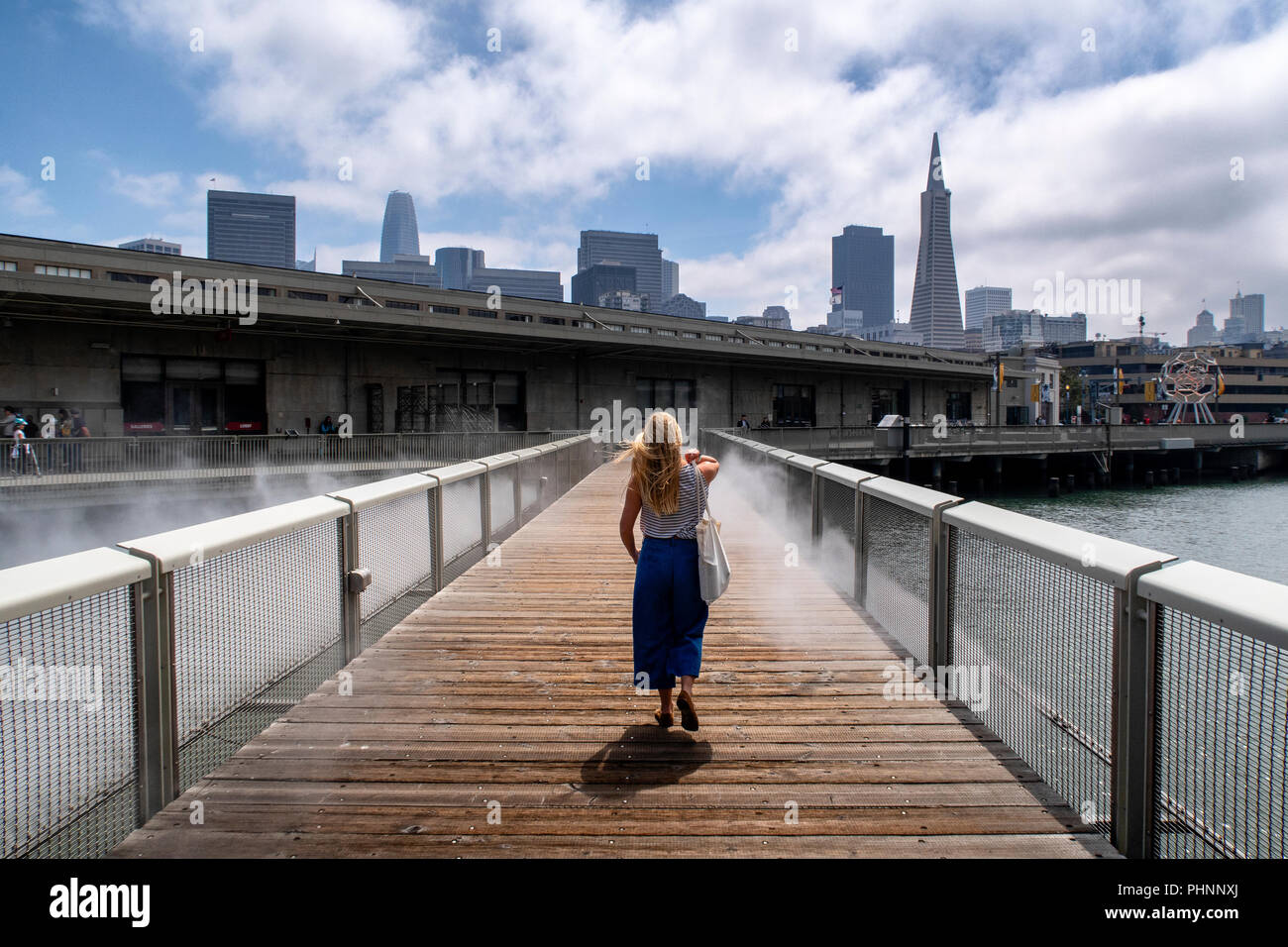 A woman walks across Fog Bridge by Fujiko Nayaka, an art installation in the waterfront area of San Francisco. Stock Photo