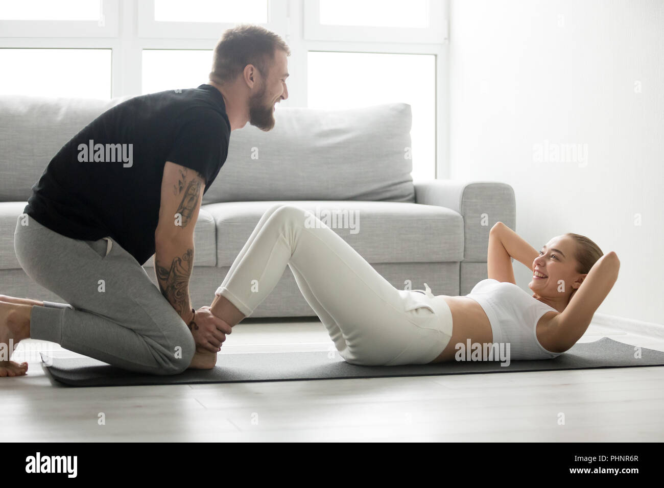 Toned woman do abs exercises supported and motivated by boyfrien Stock Photo