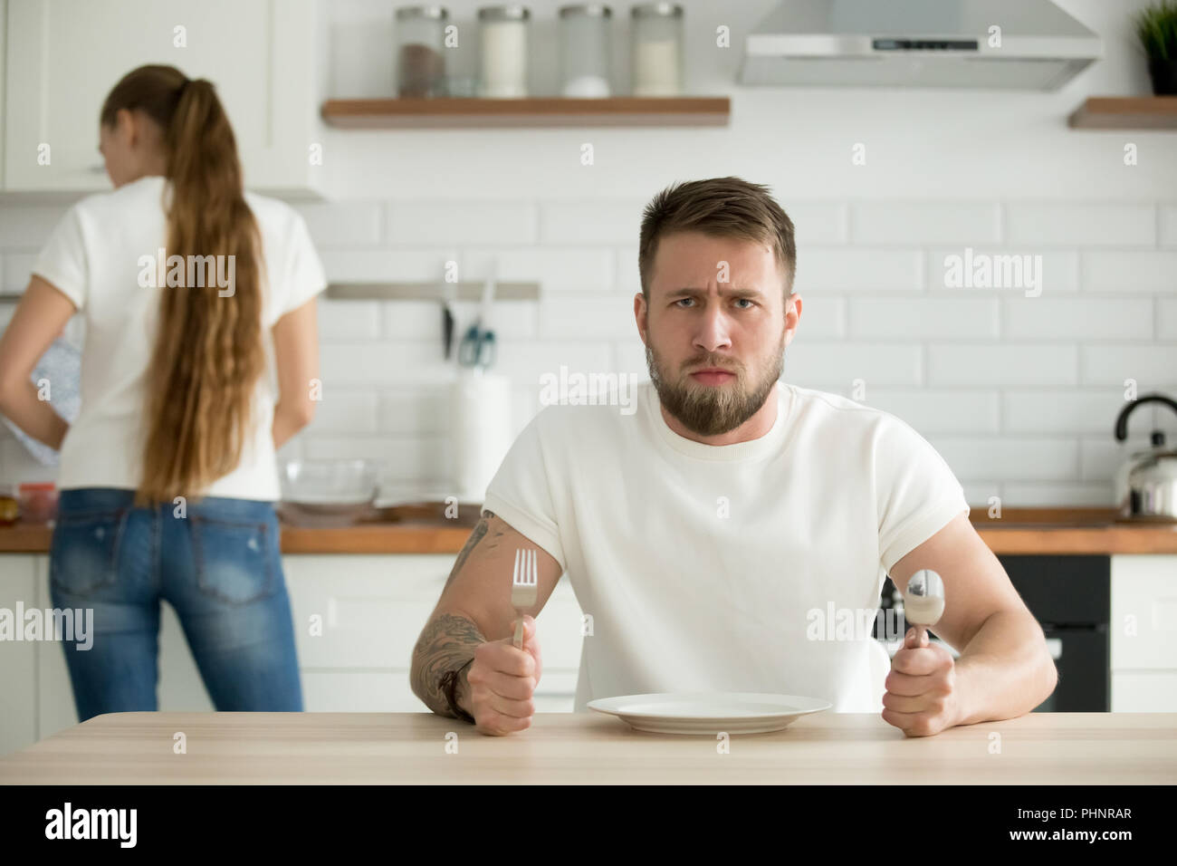 Dissatisfied man waiting for dinner cooked by wife Stock Photo
