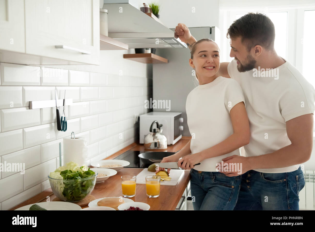 Happy young couple prepare breakfast in kitchen together Stock Photo