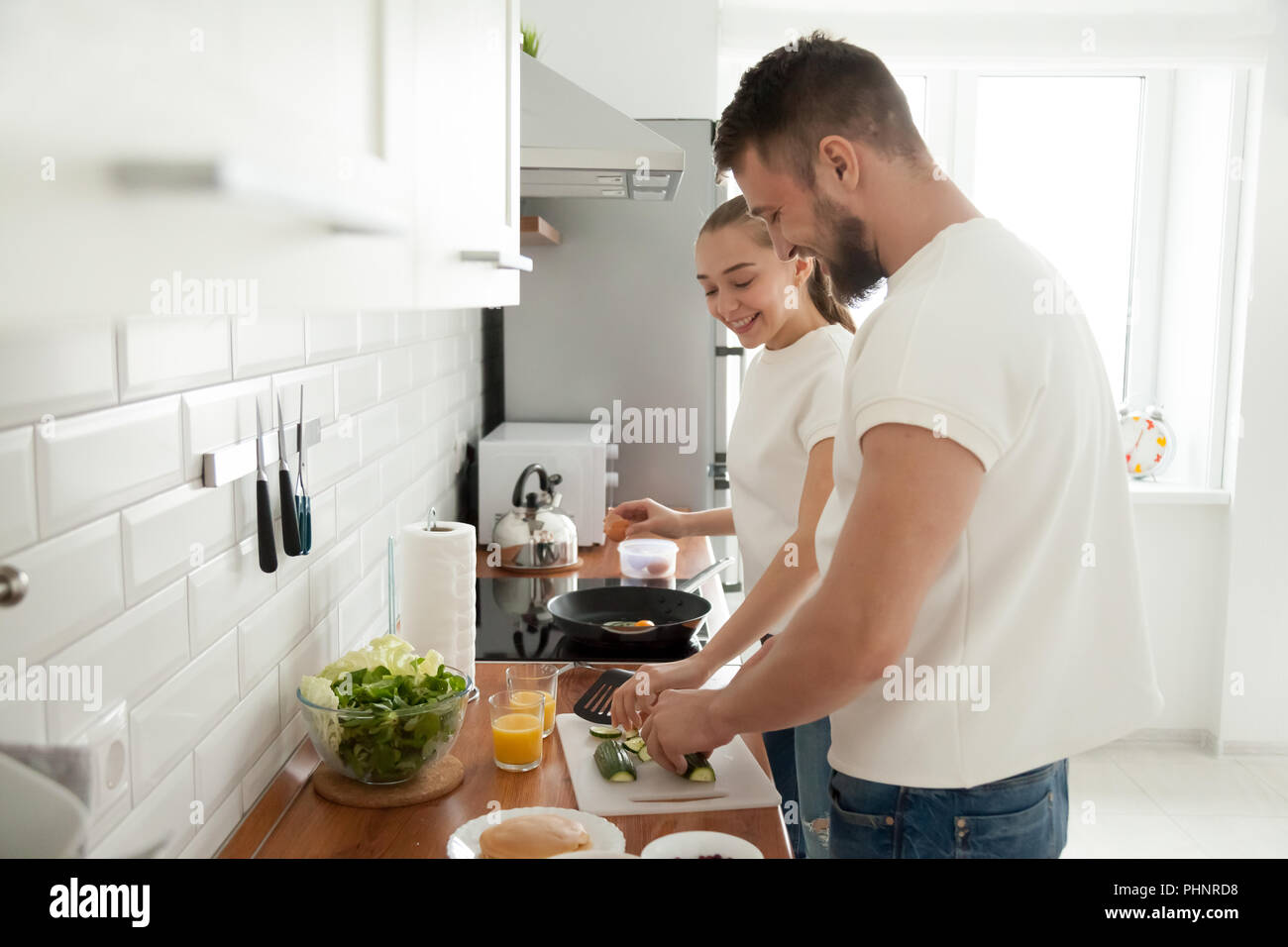 Happy couple preparing breakfast together in kitchen in morning Stock Photo