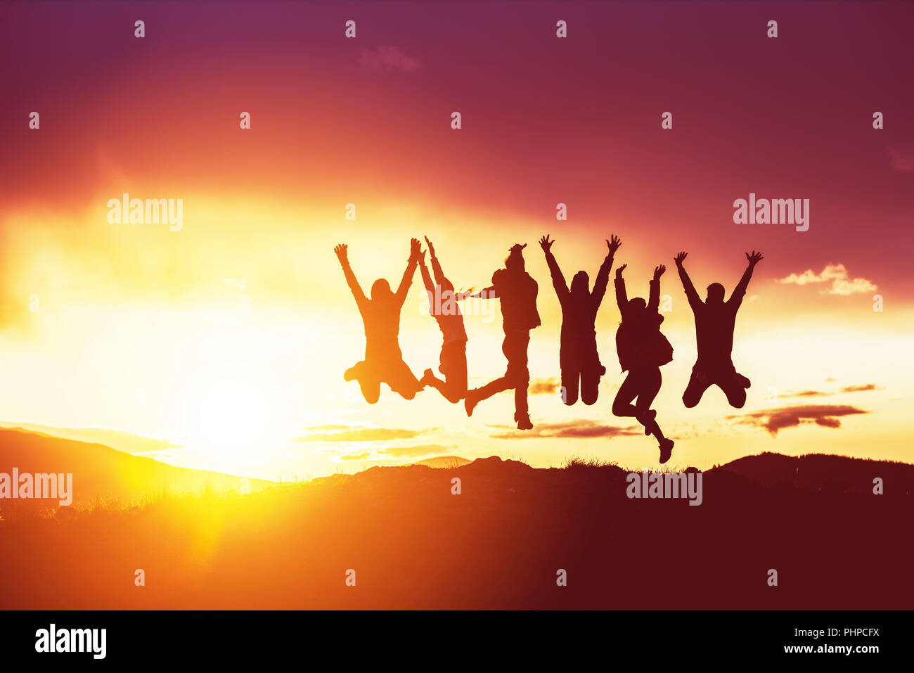 Happy friends silhouettes jumps sunset Stock Photo