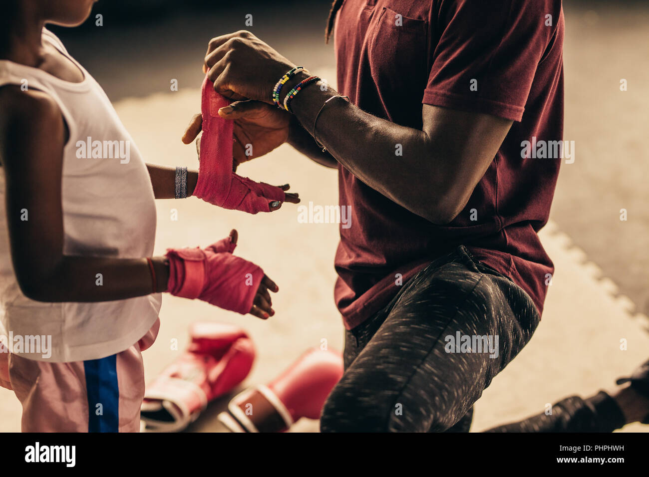 Boxing coach wrapping bandage on hands and knuckles of a kid before