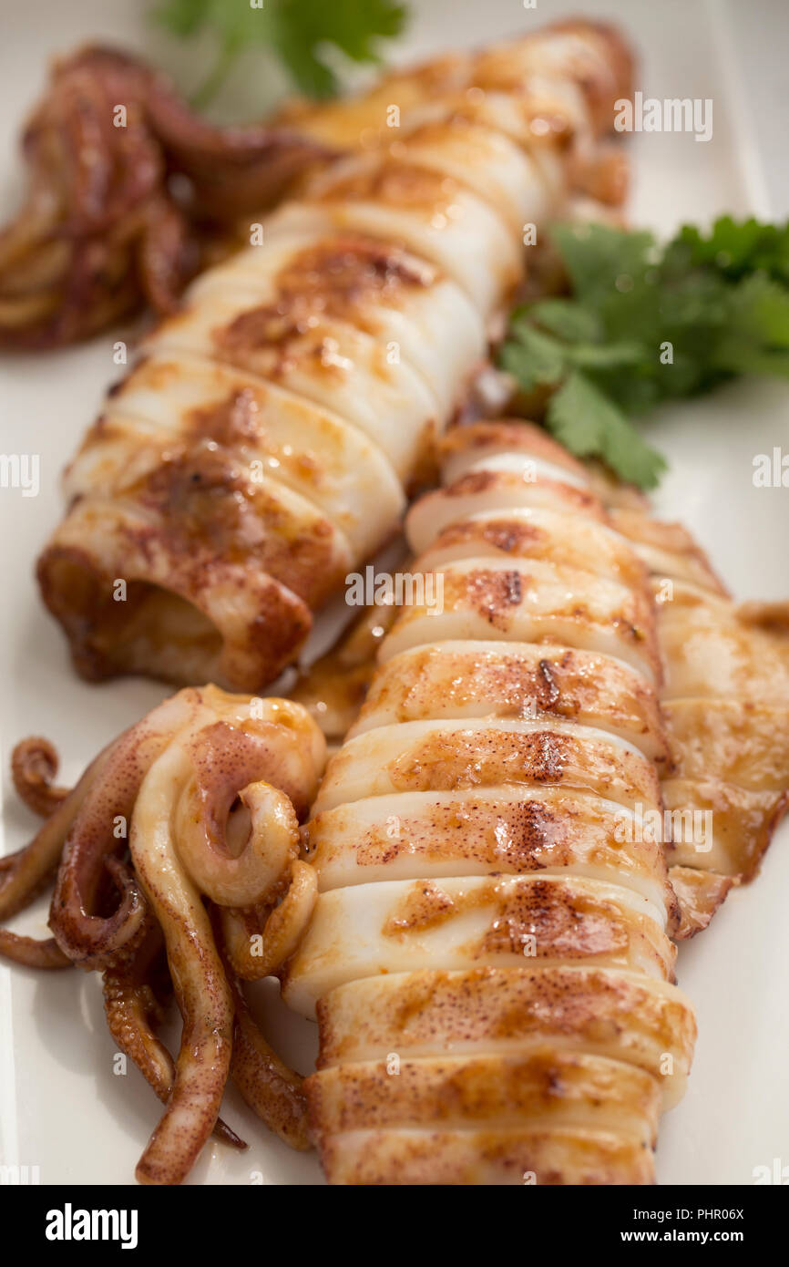 Squid, Loligo vulgaris, caught on rod and line in UK waters that have been fried with butter, vegetable oil, garlic, chili flakes and Teriyaki sauce b Stock Photo
