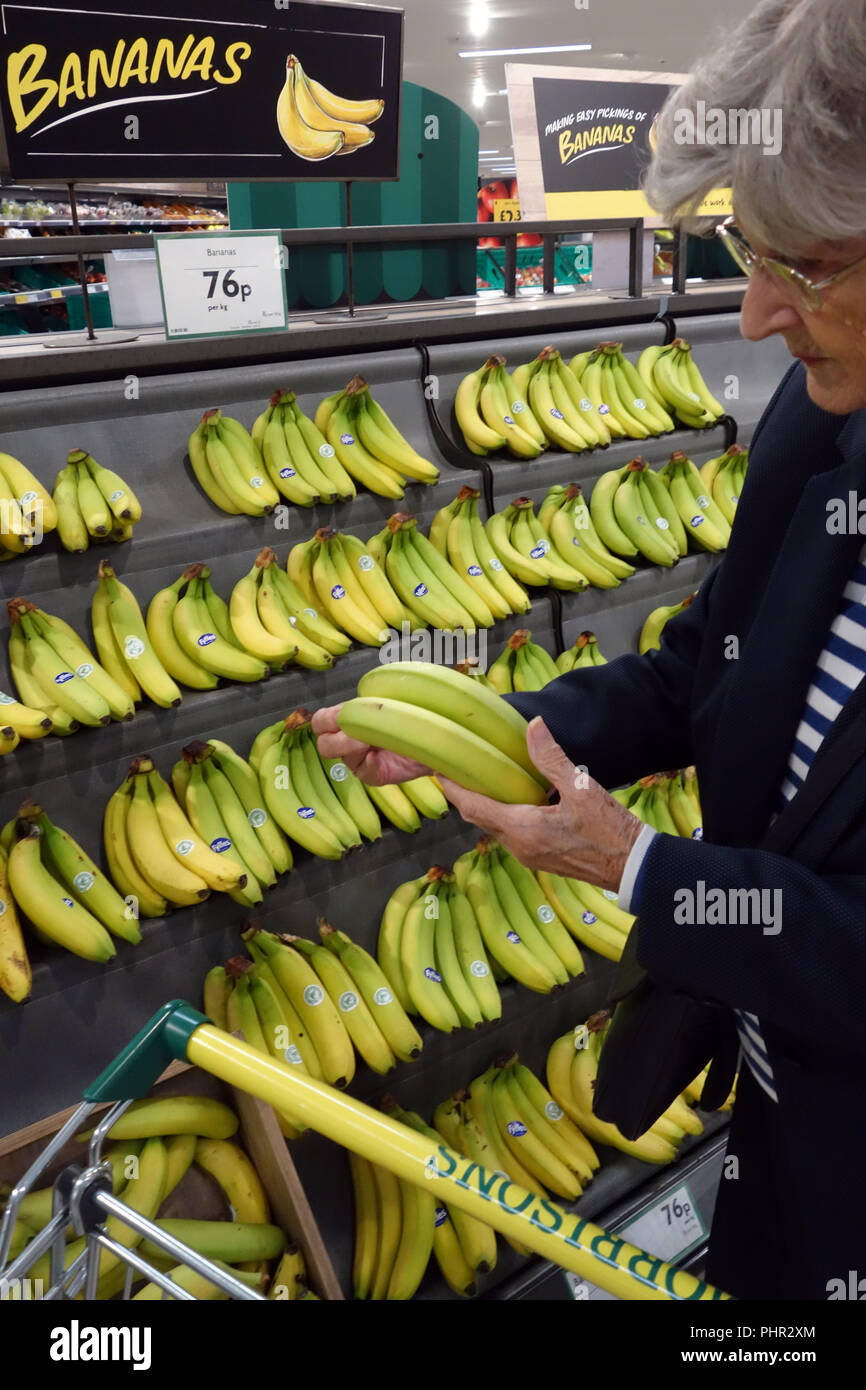 Lady buying bananas at her shopping in Morrisons supermarket aisle