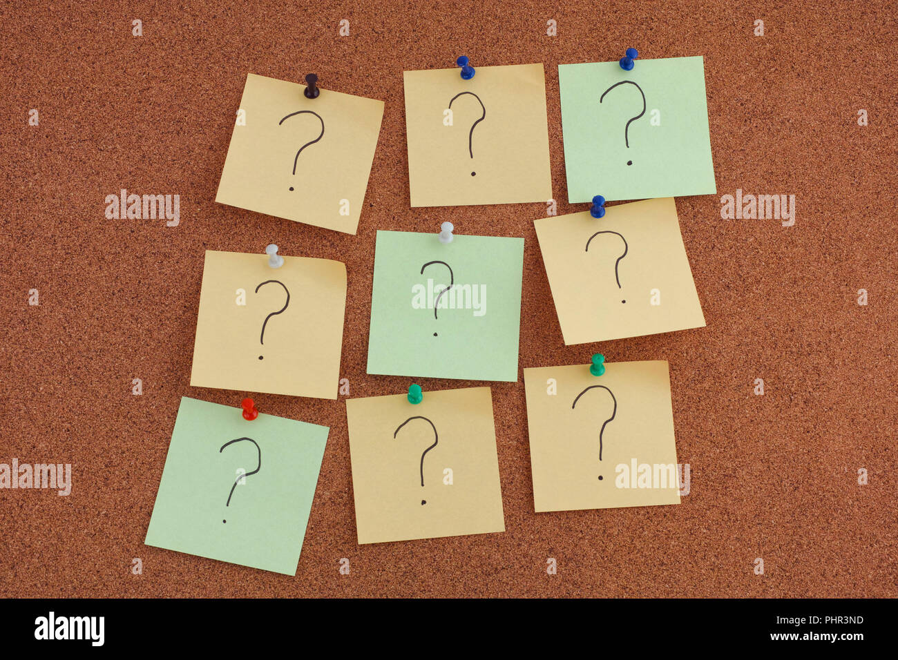Post it notes with question marks on bulletin board. Close up. Stock Photo