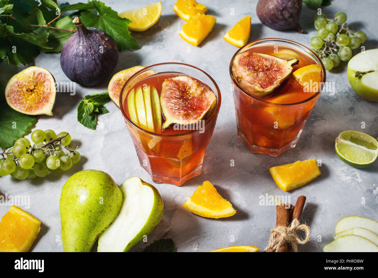 Cocktail fruit sangria with apples, orange, figs, grapes, mint on concrete table Stock Photo