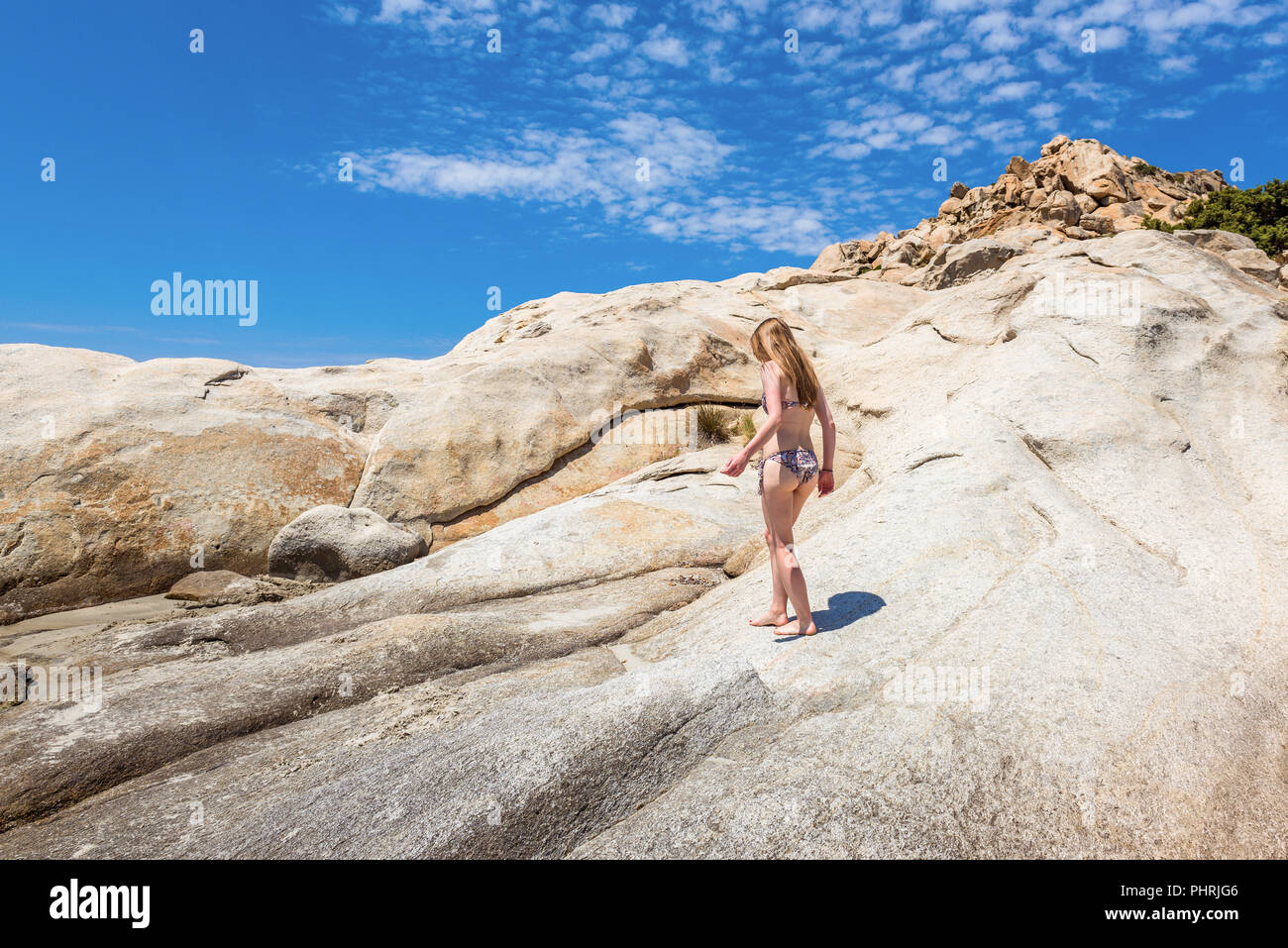 A beautiful young woman standing on a rock in summer day. Naxos, Greece Stock Photo