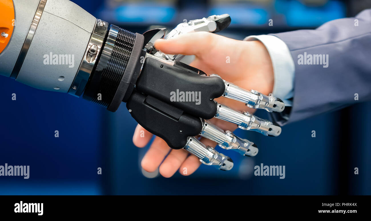 Hand of a businessman shaking hands with a droid robot. The concept of human interaction with artificial intelligence. Stock Photo