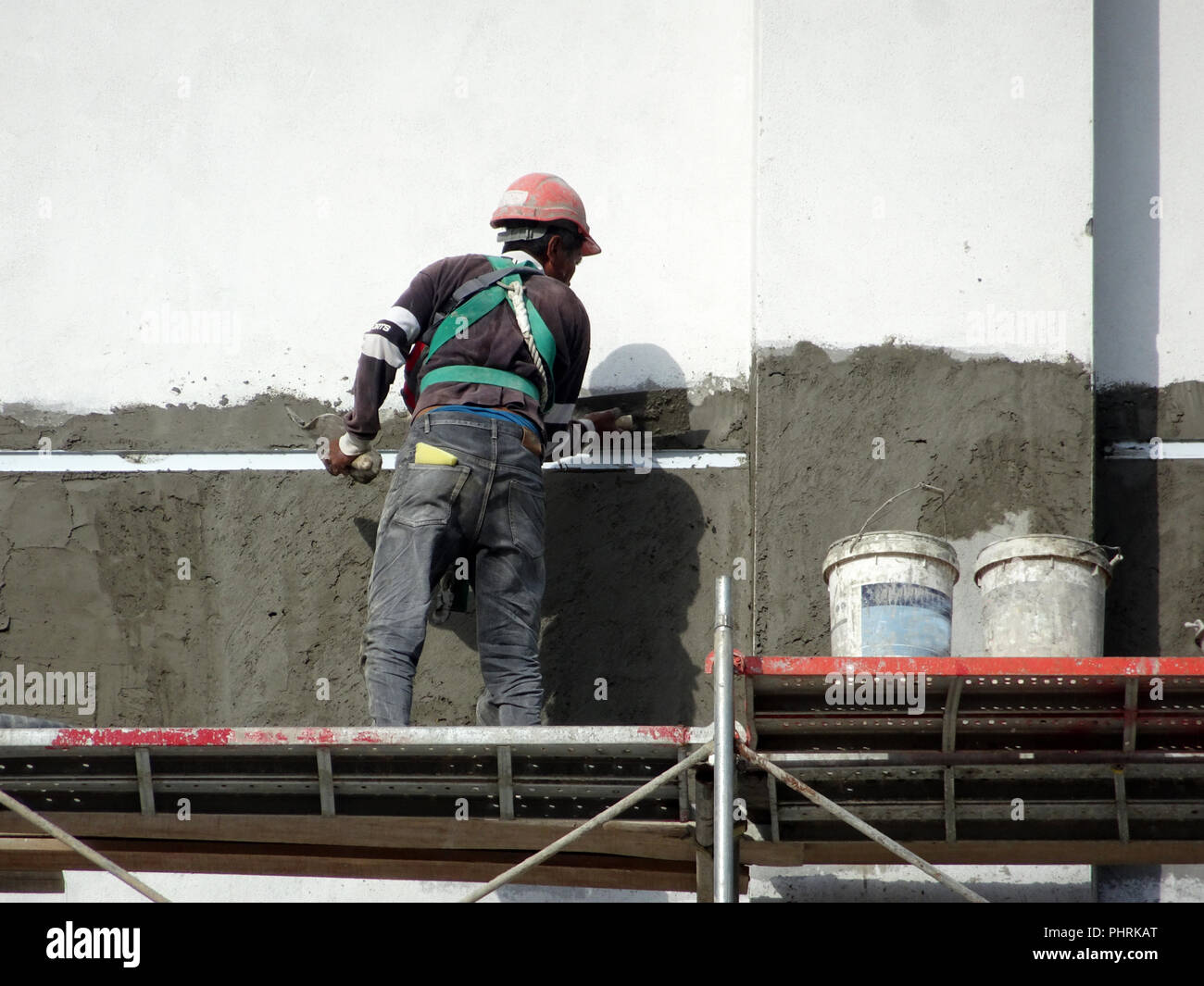 Construction workers plastering wall using cement plaster at the