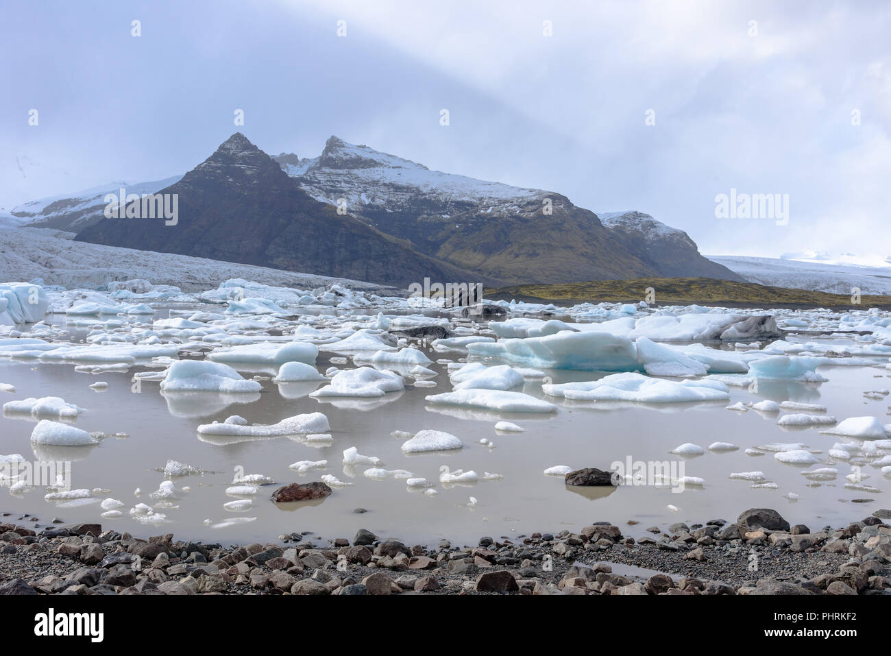 Icebergs in the Fjallsárlón glacial lake in Iceland on a day with clouds Stock Photo
