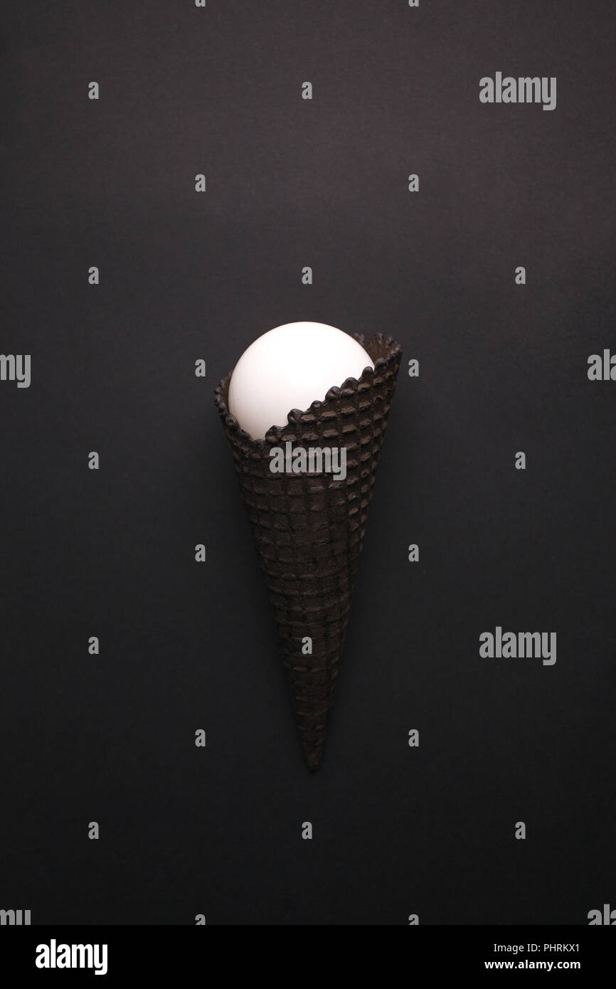 Black Ice Cream Cone with white ball on black background, monochrome party minimal closeup Stock