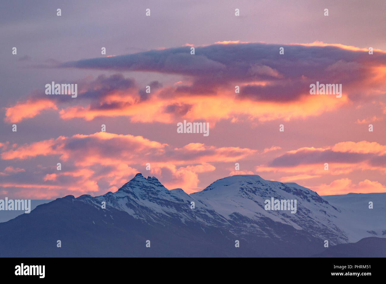 A sunset sky seen over snow-capped mountain peaks from Höfn, Iceland ...