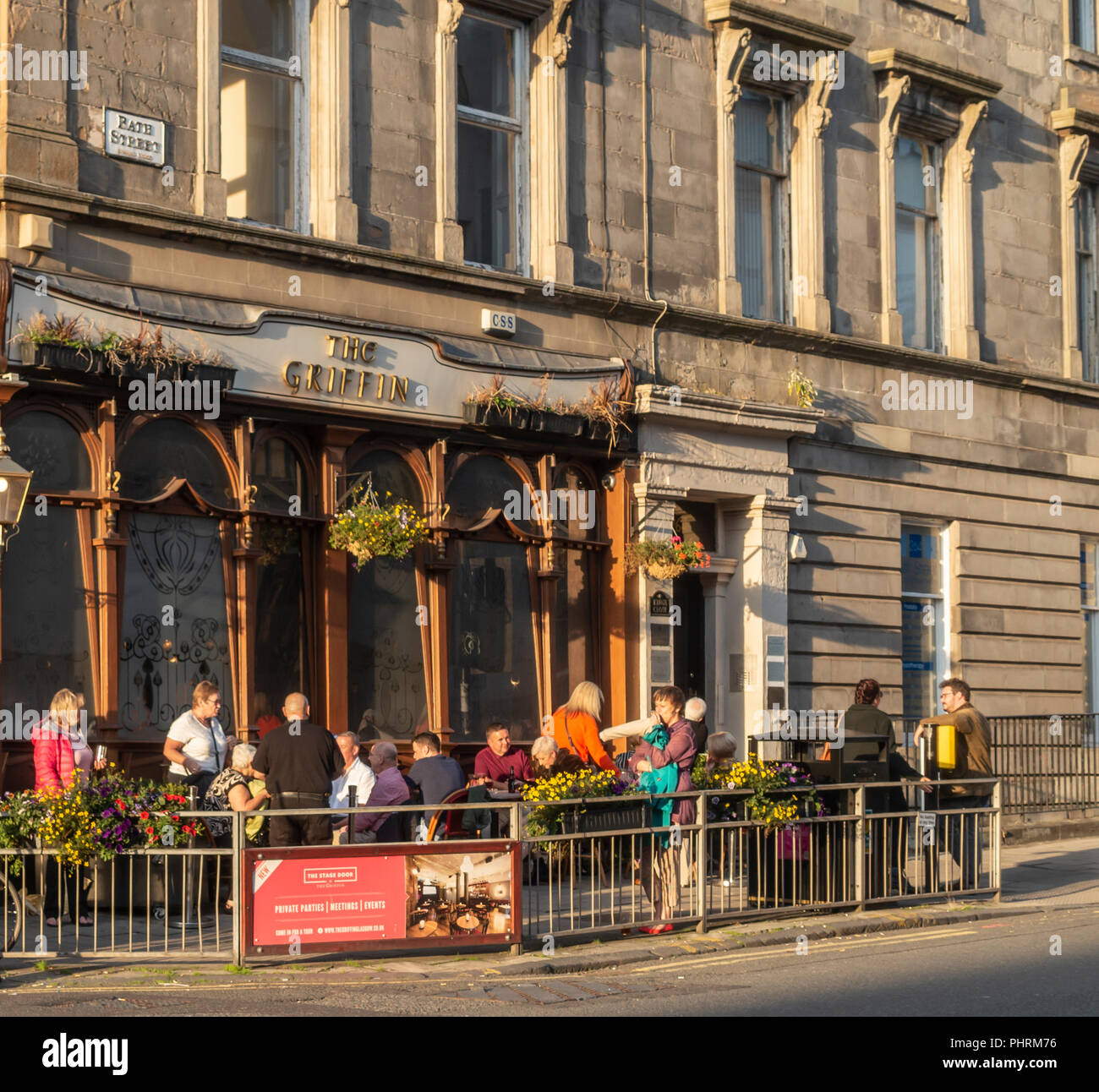 Customers enjoying evening sunshine in late August in the outdoors seated area outside the Griffin Bar, a Victorian Pub in central Glasgow, Scotland,  Stock Photo