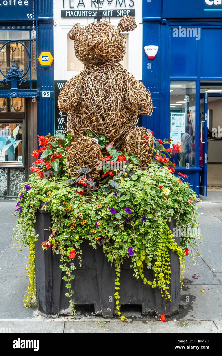 A wicker teddy bear on a flower planter in Buchanan Street, a pedestrianised shopping centre in Glasgow city centre, Scotland, UK Stock Photo