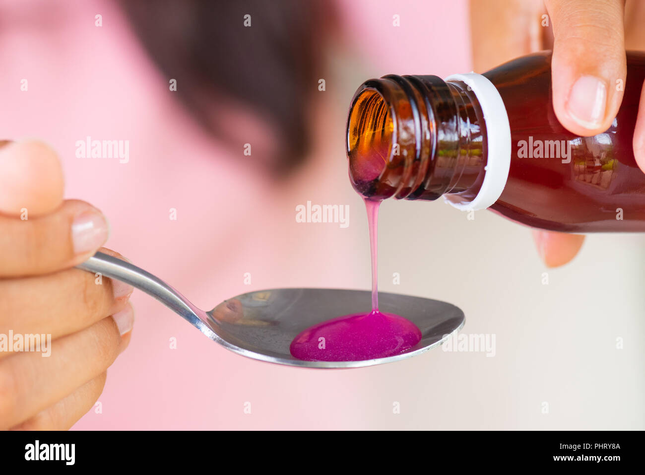 Woman hand pouring medication or antipyretic syrup from bottle to spoon. healthcare, people and