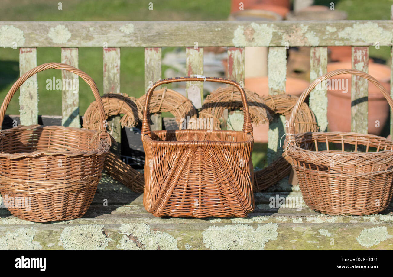a selection of wicker shopping baskets on a wooden bench on sale at a