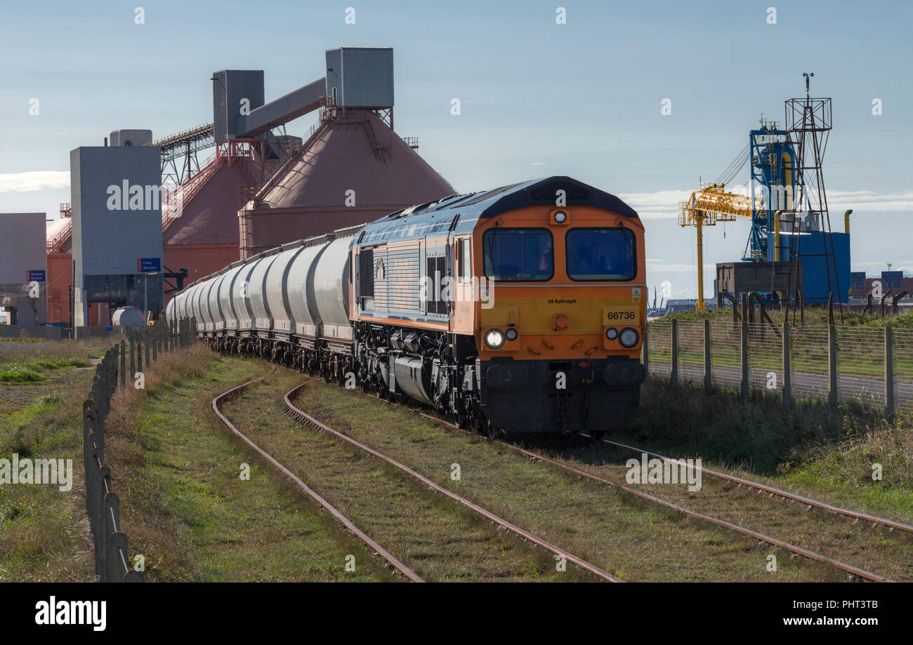 A GB Railfreight class 66 locomotive departing from North Blyth Alumina import terminal with a freight train of bulk alumina Stock Photo