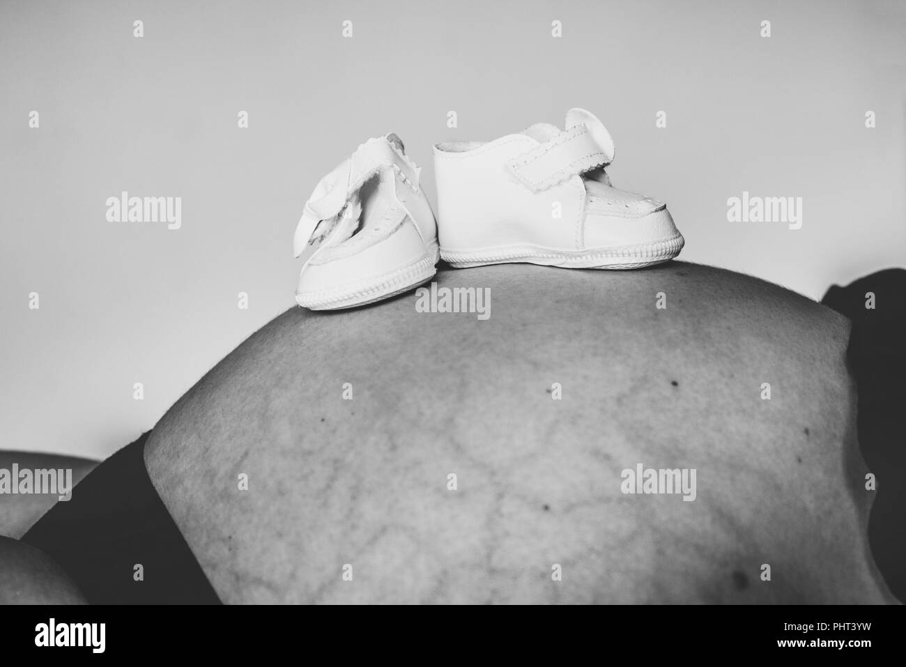 small baby boots on mother stomach, black and white Stock Photo